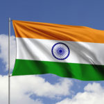 Indian flag waving against a blue sky with scattered white clouds, symbolizing the country's green hydrogen regulatory initiative.