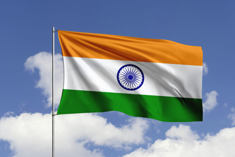 Indian flag waving against a blue sky with scattered white clouds, symbolizing the country's green hydrogen regulatory initiative.